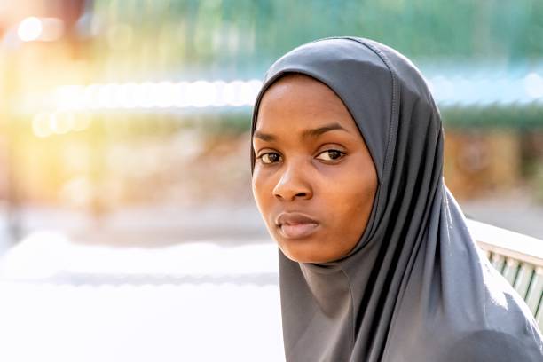 Pensive serious young black muslim woman wearing a hijab looking at the camera